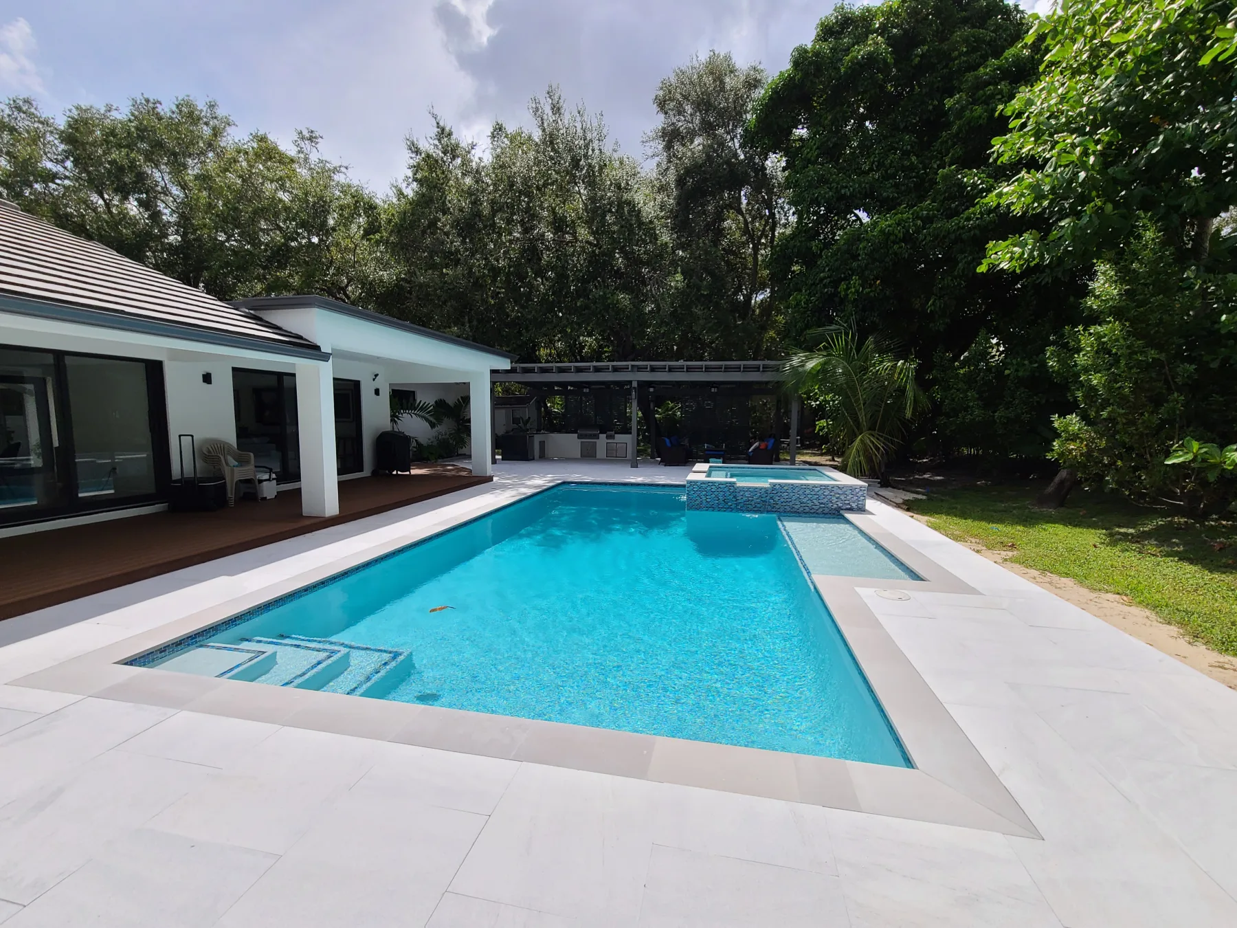 Rectangular swimming pool with pale stone patio and spa