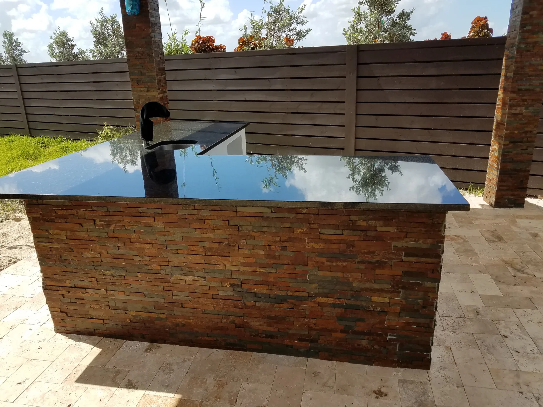 Brick-clad outdoor kitchen island with a polished countertop