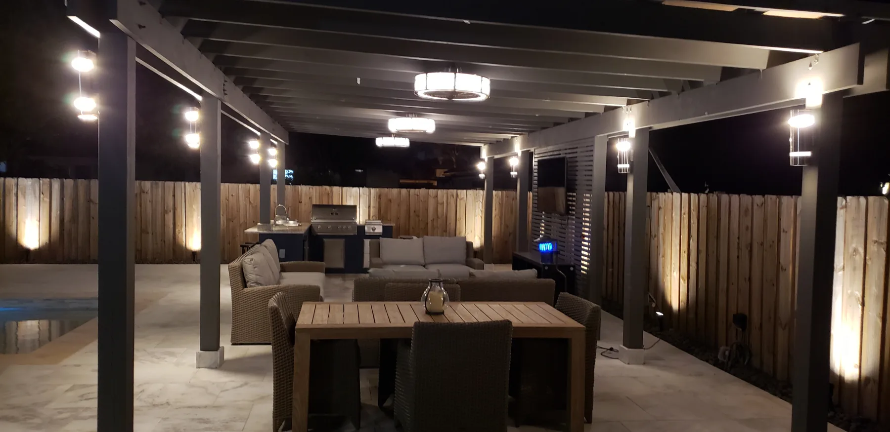 Covered outdoor dining area with ceiling lights at night