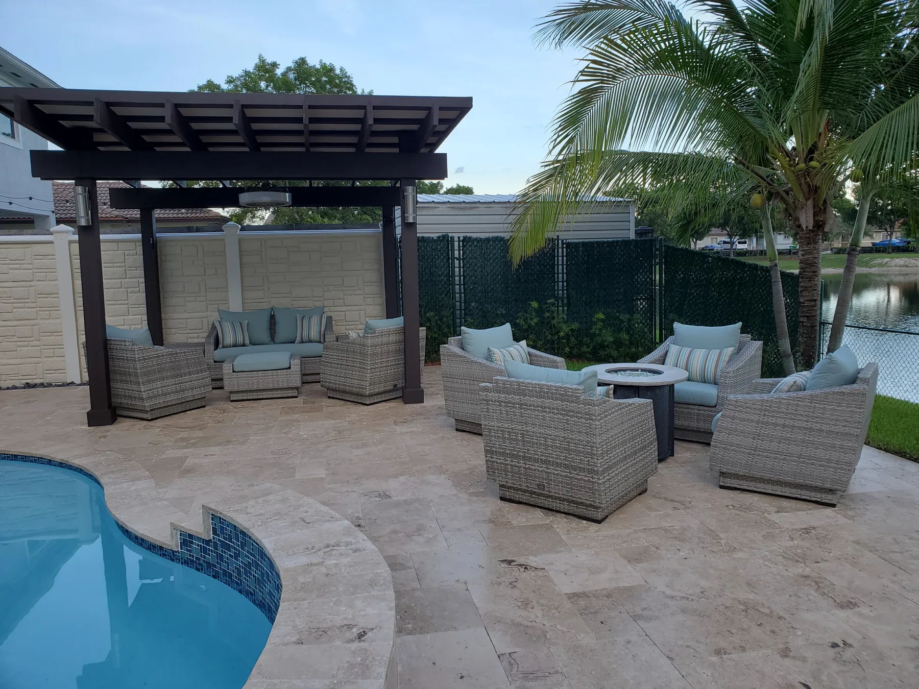 Poolside pergola with shaded seating and palm trees