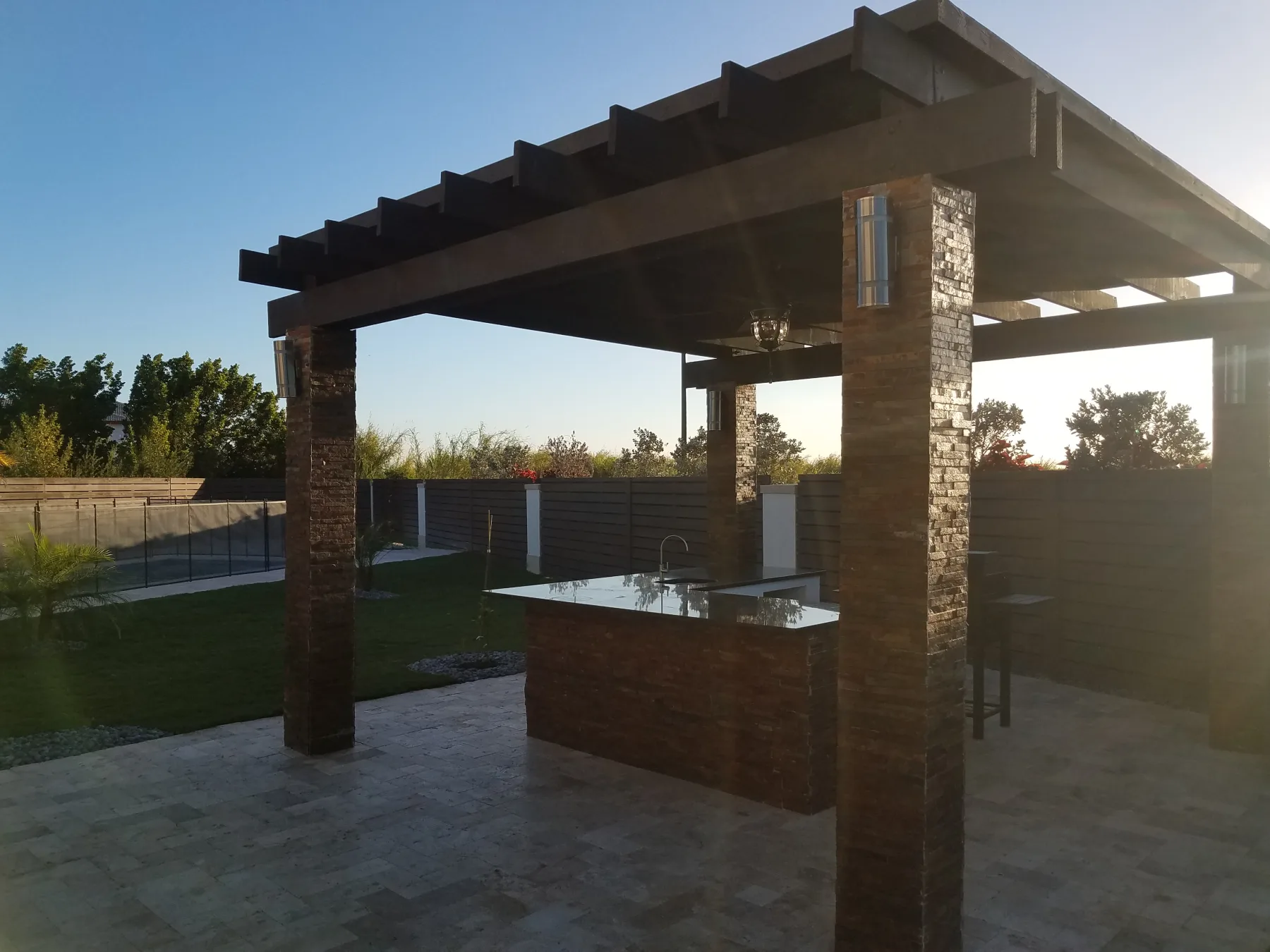 Pergola with stone columns above an outdoor kitchen island